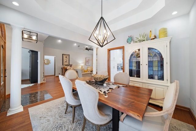 dining area featuring an inviting chandelier, wood finished floors, and ornate columns