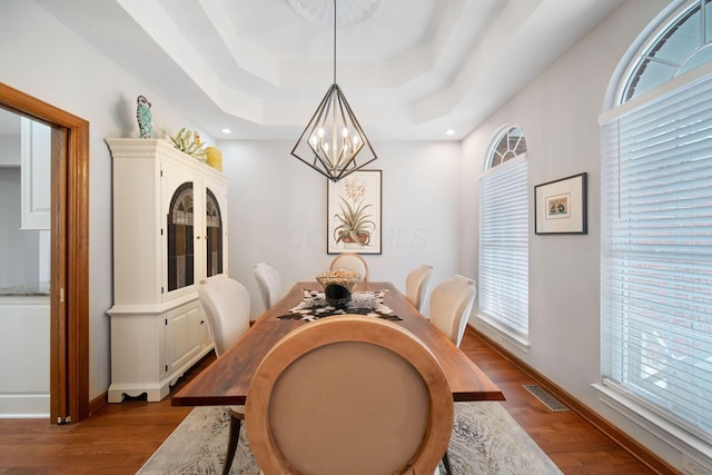 dining area with visible vents, baseboards, dark wood finished floors, a notable chandelier, and a raised ceiling
