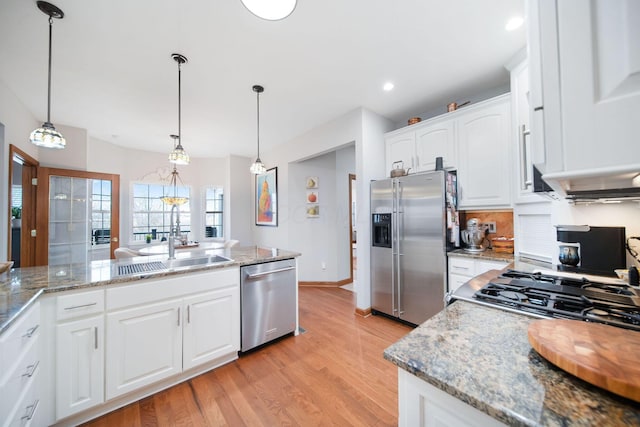 kitchen featuring white cabinets, decorative light fixtures, light wood finished floors, and stainless steel appliances