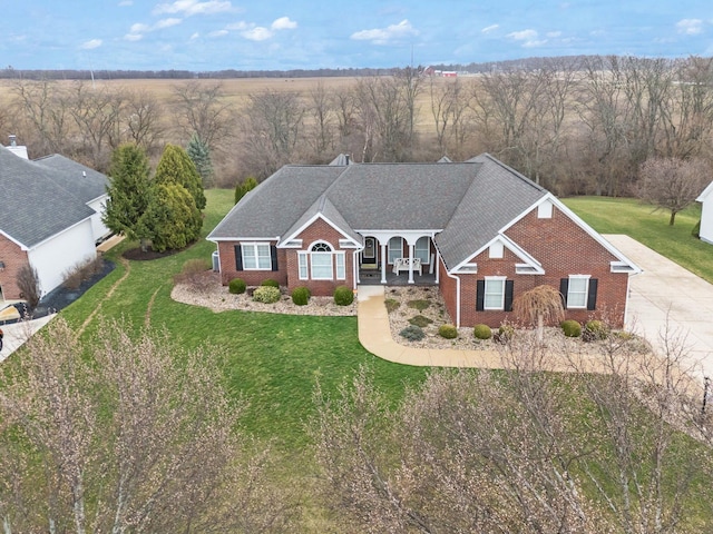 view of front of property with a front yard, brick siding, and a shingled roof