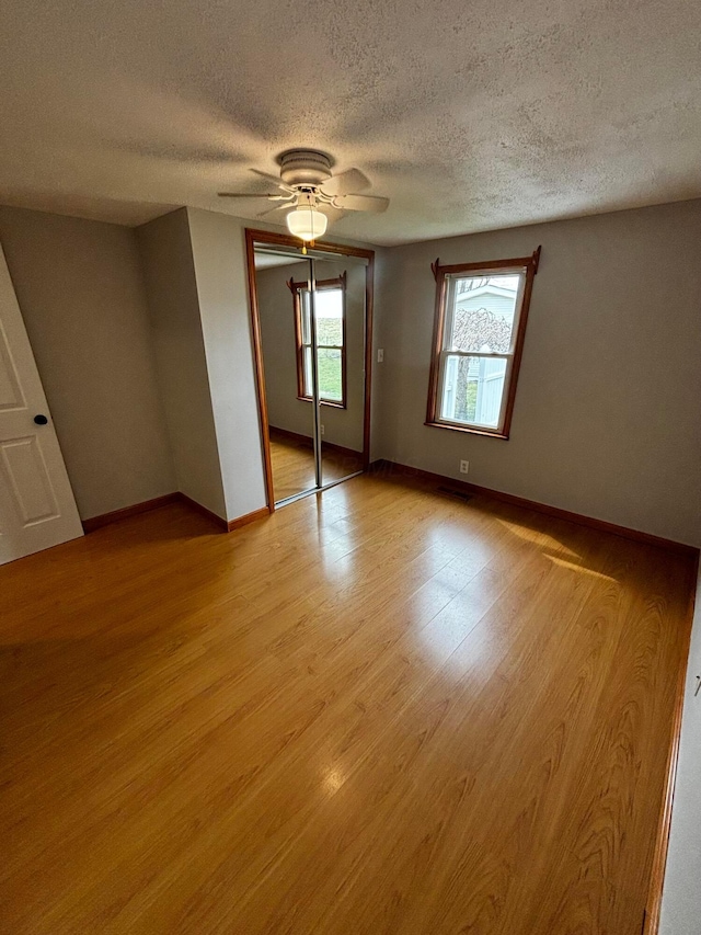 unfurnished bedroom with a ceiling fan, light wood-style flooring, a closet, and baseboards