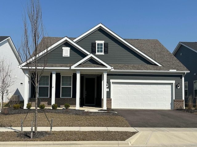 craftsman-style house with a porch, brick siding, driveway, and roof with shingles