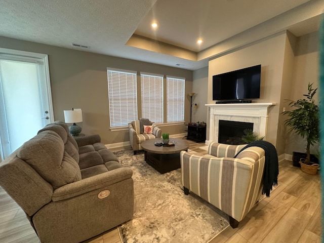 living area with light wood-style flooring, a fireplace, visible vents, and baseboards