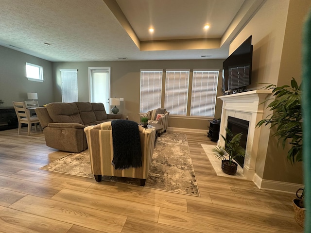 living area featuring a fireplace with flush hearth, baseboards, and light wood-type flooring