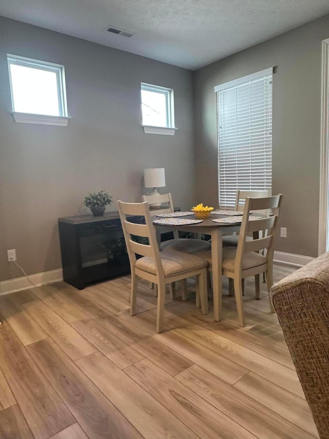 dining area with light wood finished floors, visible vents, and baseboards