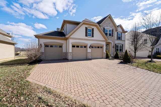 view of front of home featuring stone siding, stucco siding, a chimney, and decorative driveway