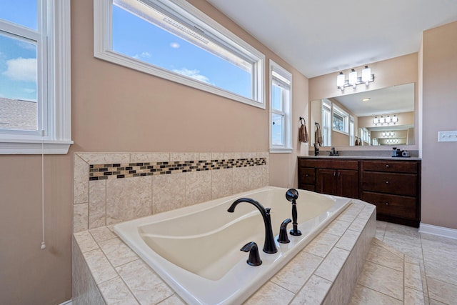 full bath with vanity, a bath, a healthy amount of sunlight, and baseboards