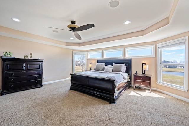 bedroom with multiple windows, baseboards, a tray ceiling, and carpet floors