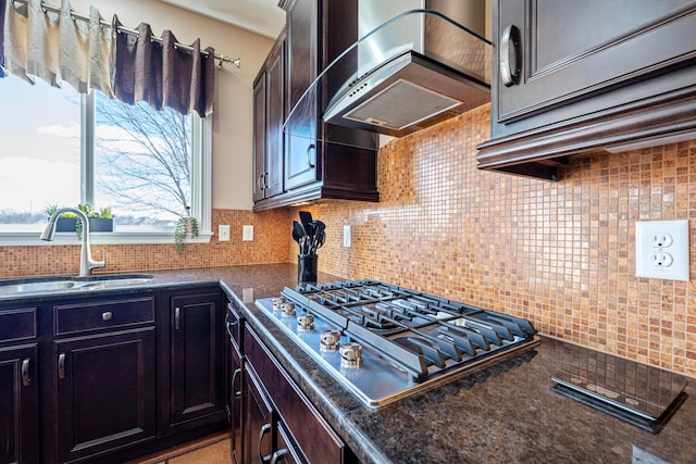 kitchen featuring a sink, tasteful backsplash, wall chimney exhaust hood, and stainless steel gas cooktop