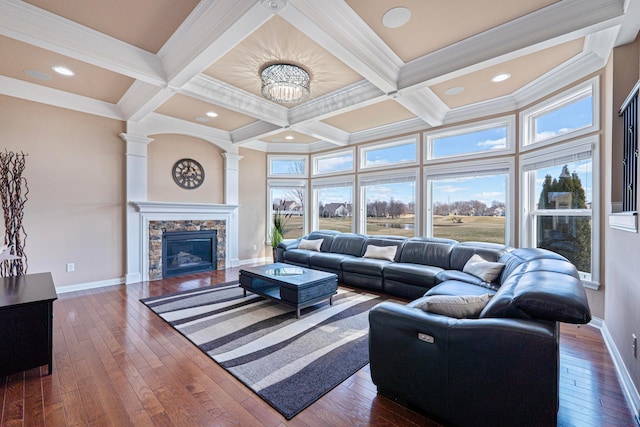 living area with beam ceiling, a stone fireplace, dark wood finished floors, and coffered ceiling