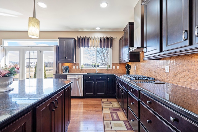 kitchen with pendant lighting, a sink, dark stone counters, appliances with stainless steel finishes, and decorative backsplash