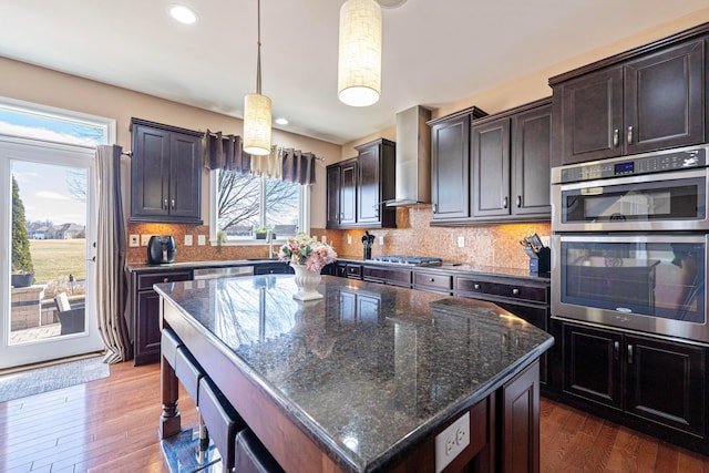 kitchen featuring dark wood-style floors, decorative backsplash, stainless steel appliances, and wall chimney exhaust hood