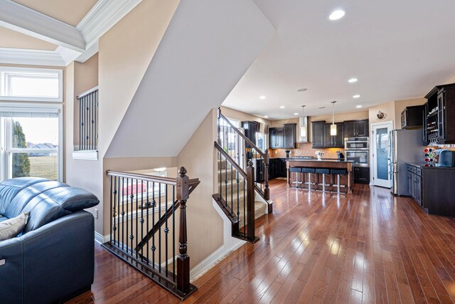 staircase featuring recessed lighting, ornamental molding, baseboards, and hardwood / wood-style flooring