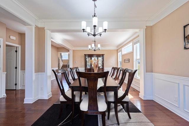 dining space with an inviting chandelier, dark wood-style floors, a wealth of natural light, and wainscoting