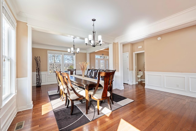 dining room featuring visible vents, an inviting chandelier, hardwood / wood-style floors, and ornamental molding