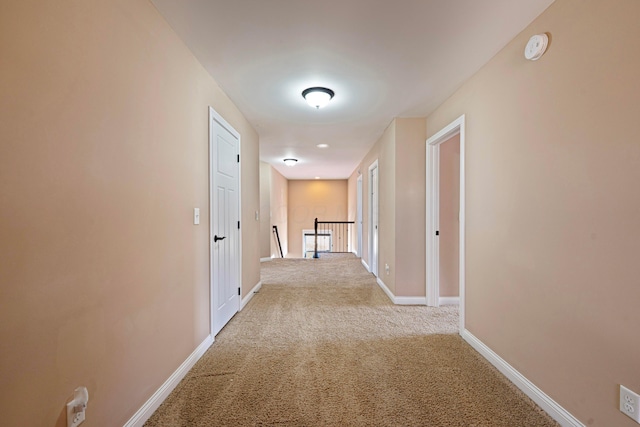 hall with baseboards, carpet floors, and an upstairs landing