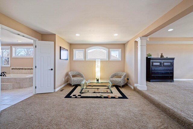 living area featuring carpet, baseboards, and ornate columns