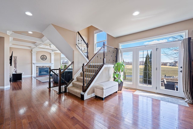 staircase with a healthy amount of sunlight, a fireplace, baseboards, and hardwood / wood-style floors