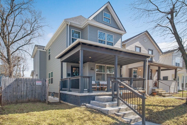 view of front of home with a front yard, fence, a porch, a shingled roof, and board and batten siding