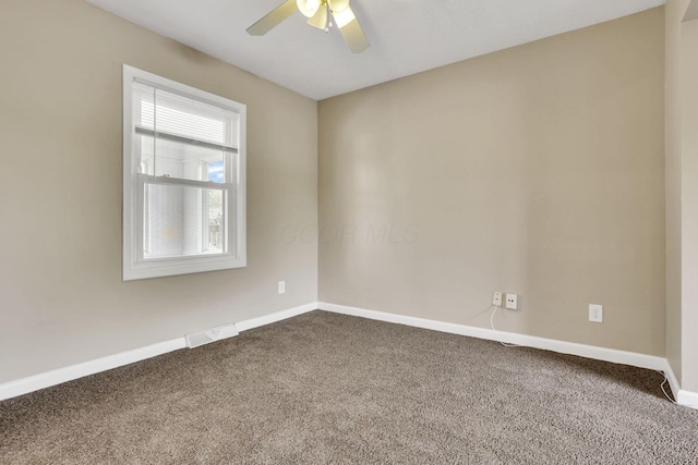 unfurnished room featuring dark colored carpet, a ceiling fan, and baseboards