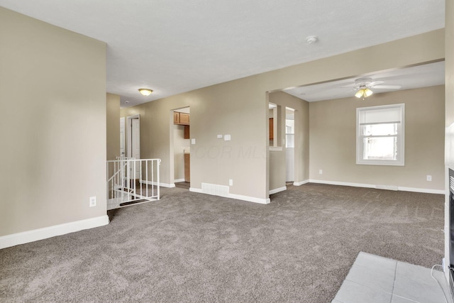 spare room featuring carpet, a ceiling fan, and baseboards