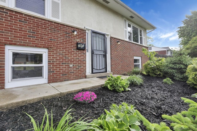 entrance to property featuring brick siding and stucco siding