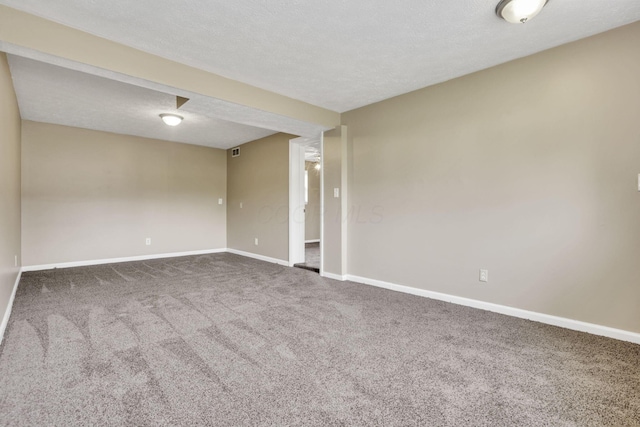 carpeted empty room with baseboards and a textured ceiling