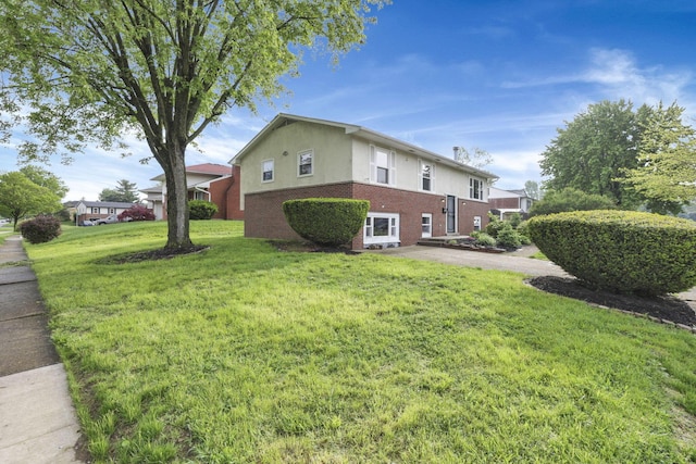 view of side of property featuring brick siding, stucco siding, and a lawn
