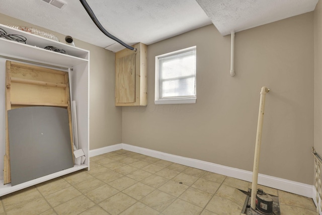 washroom featuring a textured ceiling and baseboards
