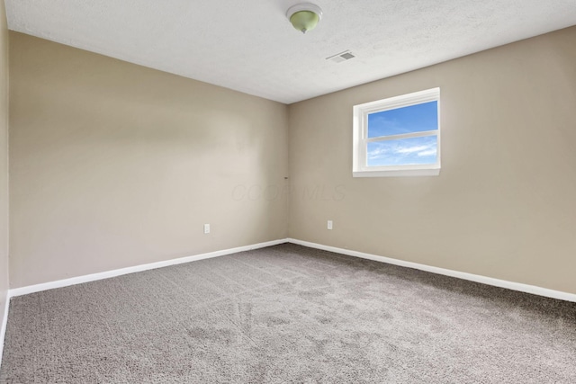 carpeted spare room featuring baseboards and a textured ceiling