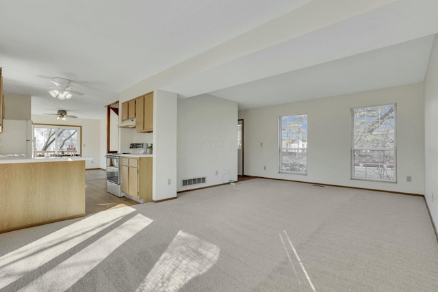 unfurnished living room with baseboards, visible vents, and light carpet