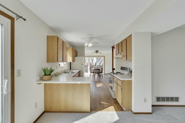 kitchen with visible vents, under cabinet range hood, light countertops, white appliances, and a sink