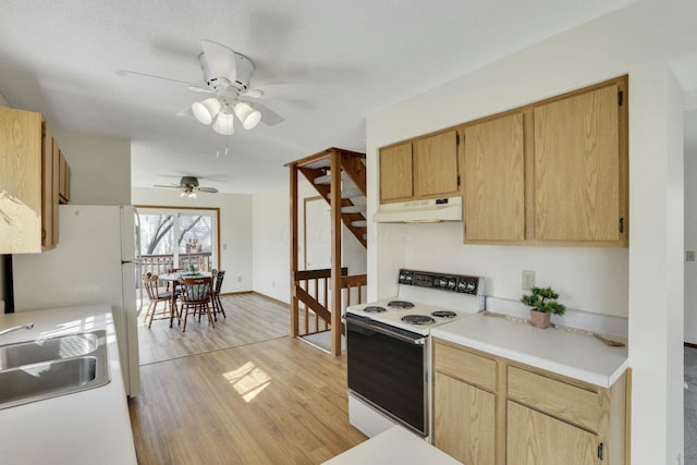 kitchen featuring light wood-type flooring, under cabinet range hood, a sink, white appliances, and light countertops