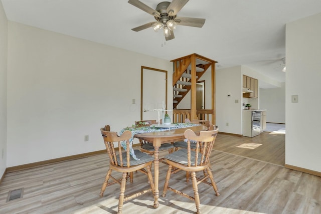 dining space with baseboards, a ceiling fan, visible vents, and light wood-type flooring