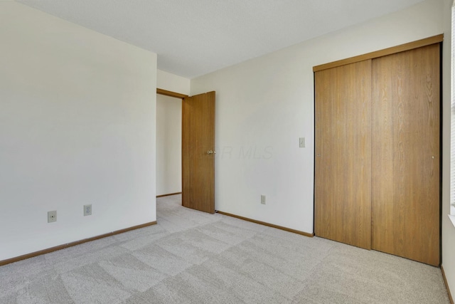 unfurnished bedroom featuring baseboards, a closet, and light carpet