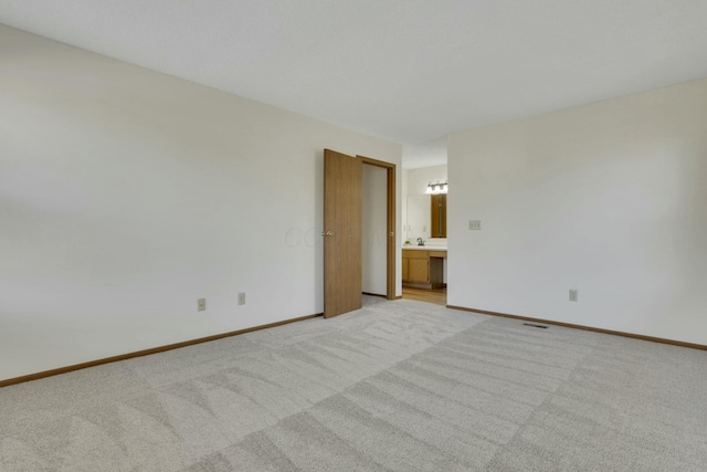 spare room featuring a sink, baseboards, and light carpet