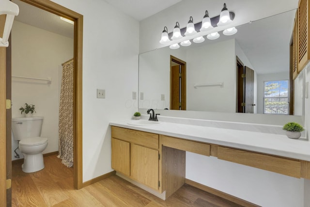 bathroom with baseboards, toilet, wood finished floors, and vanity