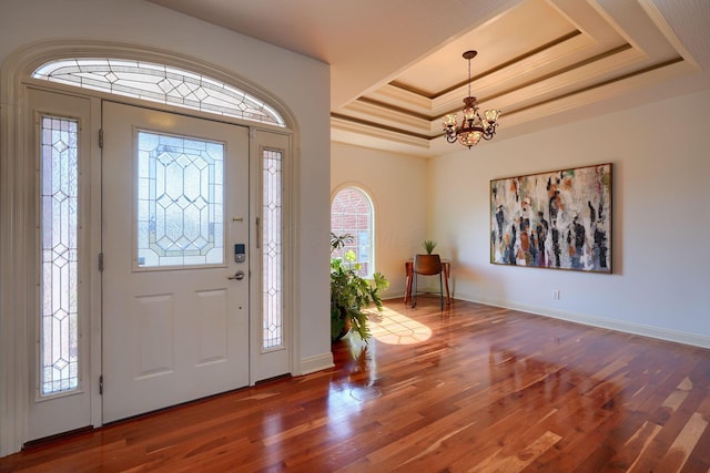 entrance foyer with a tray ceiling, an inviting chandelier, and wood finished floors