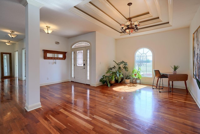 entryway featuring crown molding, baseboards, an inviting chandelier, wood finished floors, and a raised ceiling