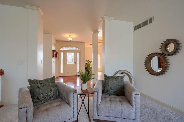 entrance foyer with wood finished floors, decorative columns, baseboards, and visible vents