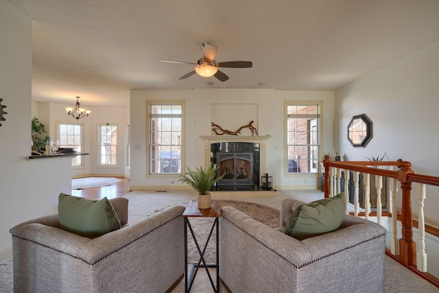 living area featuring ceiling fan with notable chandelier, baseboards, a wealth of natural light, and a premium fireplace