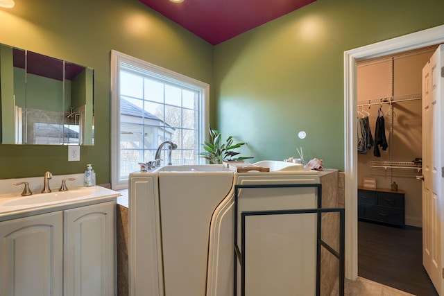 full bathroom with vanity, wood finished floors, a freestanding tub, a spacious closet, and a shower