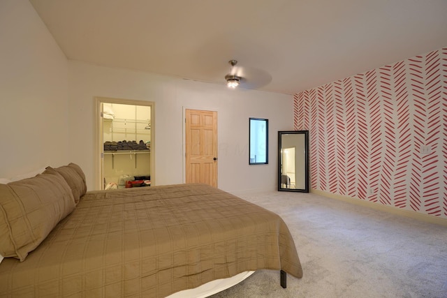 bedroom with a walk in closet, baseboards, light carpet, a closet, and a ceiling fan