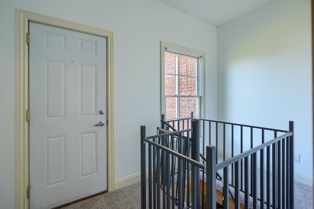 hallway featuring an upstairs landing, carpet flooring, and baseboards