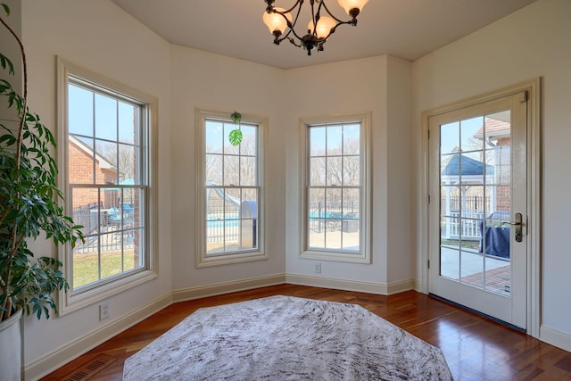 doorway with baseboards, dark wood-style floors, visible vents, and a chandelier