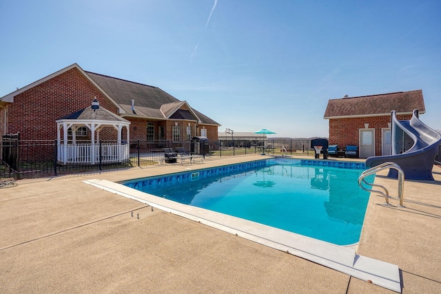 view of pool featuring a patio area, a fenced in pool, a water slide, and fence