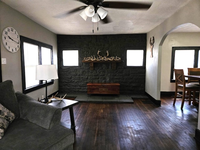 living room featuring baseboards, arched walkways, a textured ceiling, and wood-type flooring