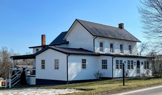 exterior space featuring metal roof, a lawn, and a chimney