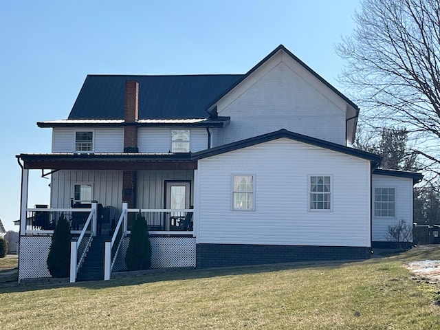 rear view of property with stairway, a lawn, covered porch, and a chimney