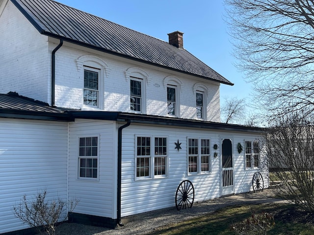 view of front facade with a chimney, a standing seam roof, and metal roof